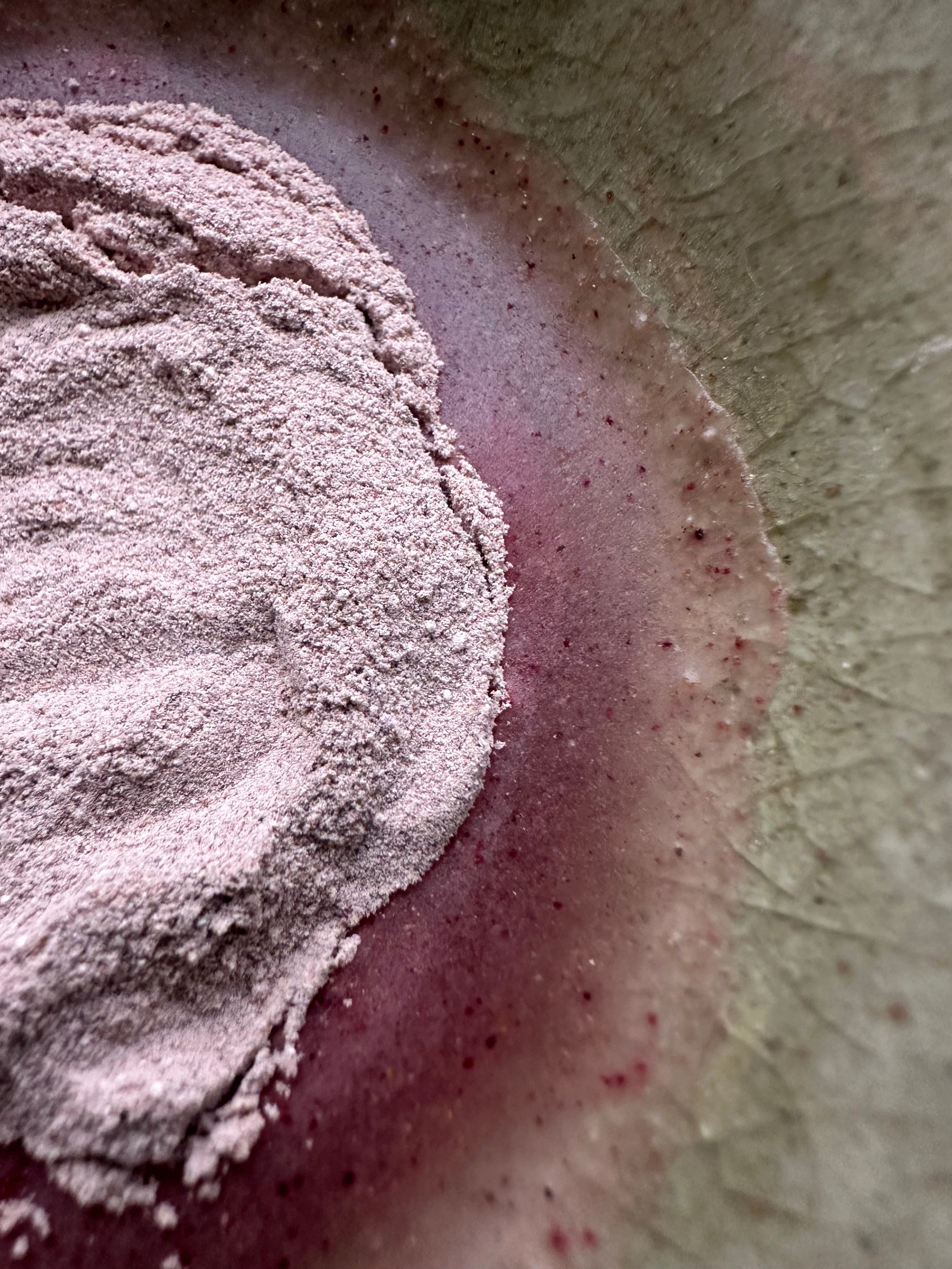 AKINA Clay Ceremony powder mask being mixed with water, showing fine botanical powder and mineral-rich texture